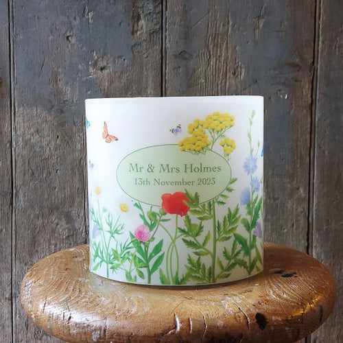 Personalized candle with floral design and text on a wooden surface