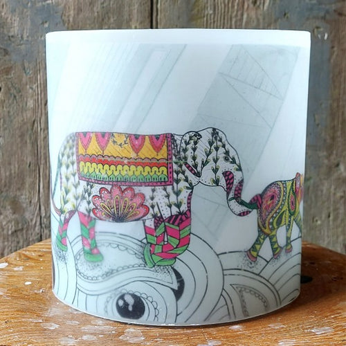 Candle with colorful elephant design on a wooden surface