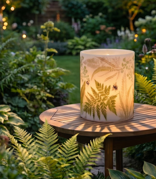 Fern Hurricane Candle in a grden sing on a table