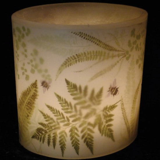 Candle holder with fern leaf design on a dark background