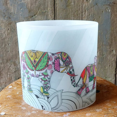 Candle with a colorful elephant design on a wooden surface