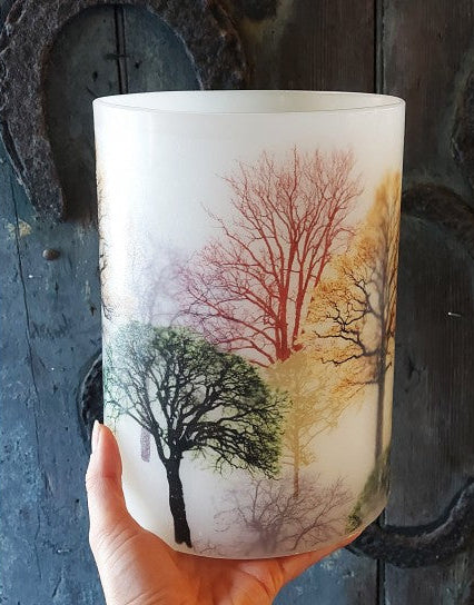 Candle with tree design held against a rustic wooden background