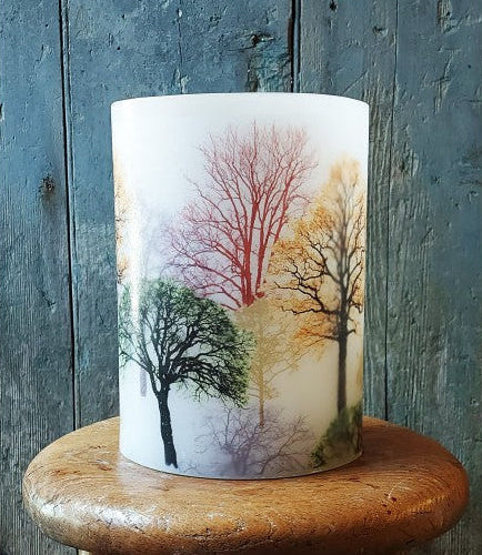 Candle with tree design on a wooden stand against a rustic wooden background