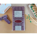 Wax Melt bar with packaging labeled 'On a Wick & Prayer' fragrance Amber and Cassis on a wooden surface with matches.