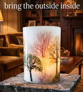 Tall hurricane candle lit on an onyx table in a sitting room