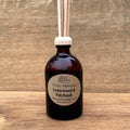Aromatherapy cedarwood and patchouli diffuser bottle with wooden sticks on a wooden background