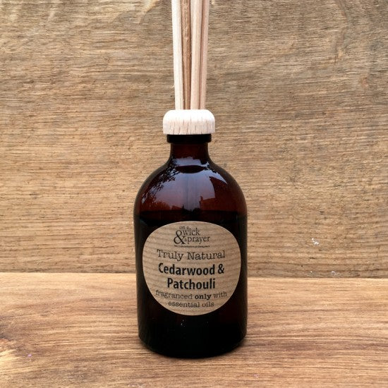 Aromatherapy cedarwood and patchouli diffuser bottle with wooden sticks on a wooden background