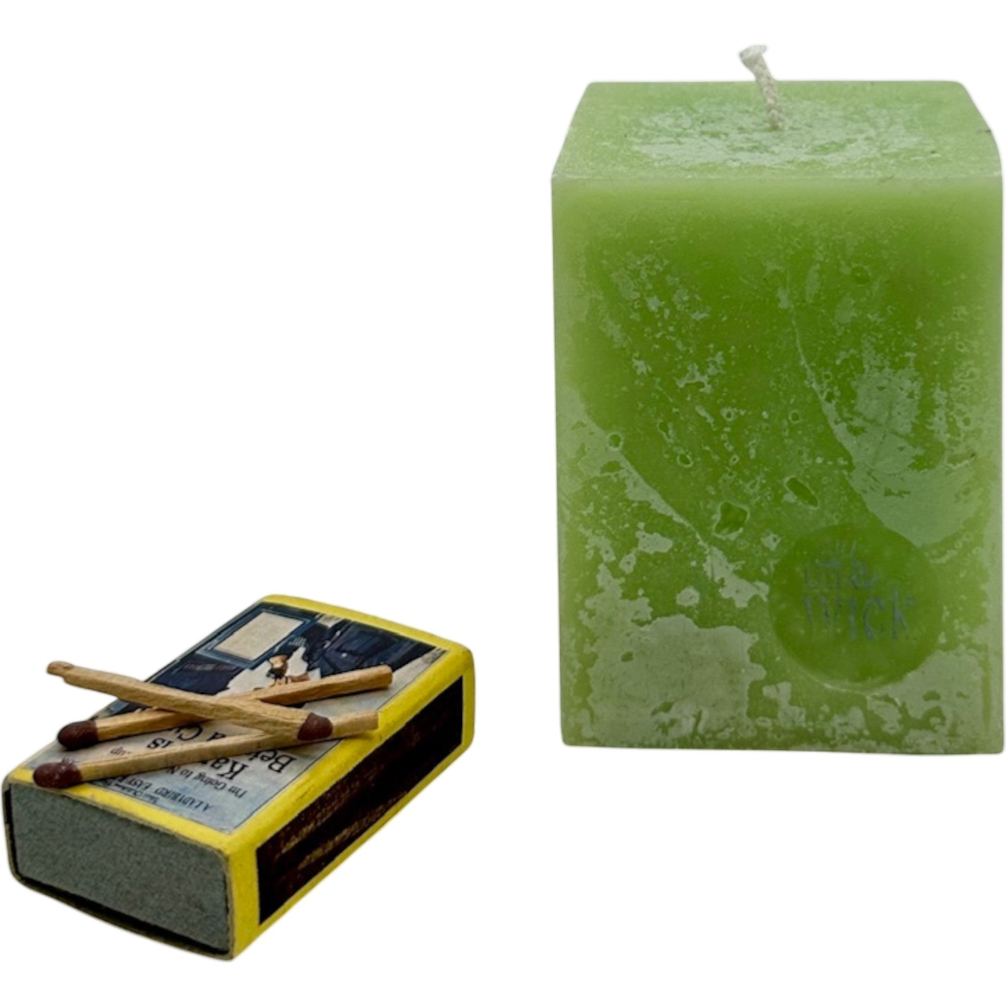 On a Wick and a Prayer lime green square pillar candle with a textured finish, next to a vintage matchbox with matches.