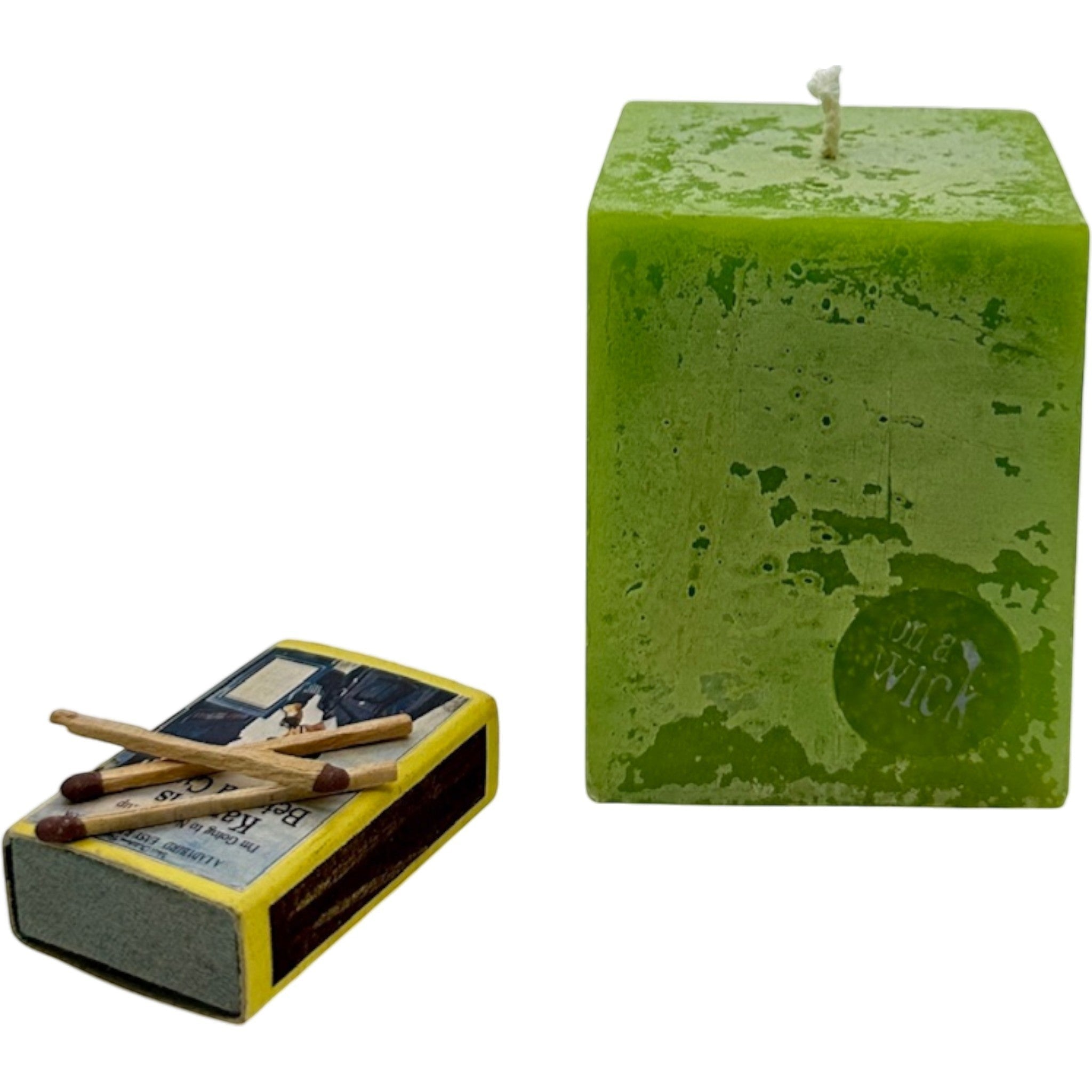 On a Wick and a Prayer lime green square pillar candle with a textured finish and a box of matches.
