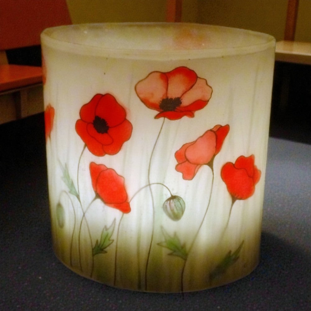 Decorative hurricane candle holder with red floral design on a dark surface